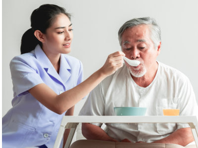 caregiver feeding the senior man