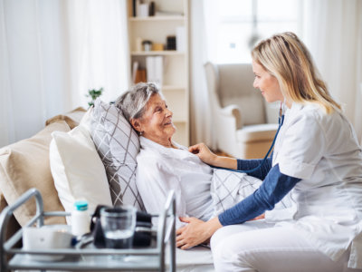caregiver listening to the senior woman's heartbeat with a stethoscope