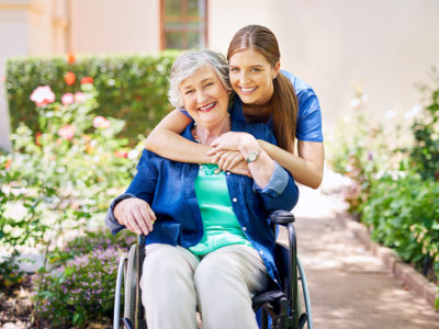 caregiver hugging senior woman in a wheelchair