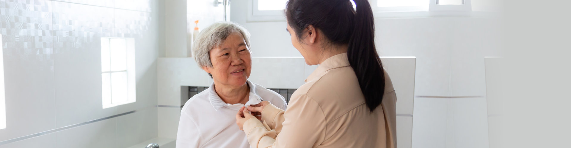 caregiver buttoning patient's shirt