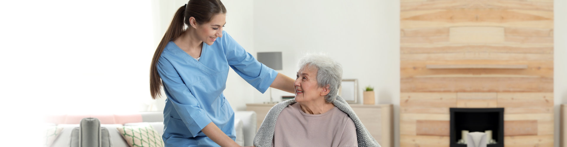 caregiver putting towel on senior woman's shoulder